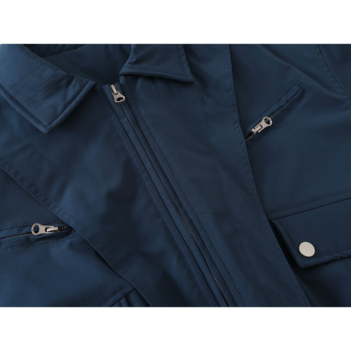 Close-up of a dark navy jacket front with a zipper, zip pockets, flap, and snap button.