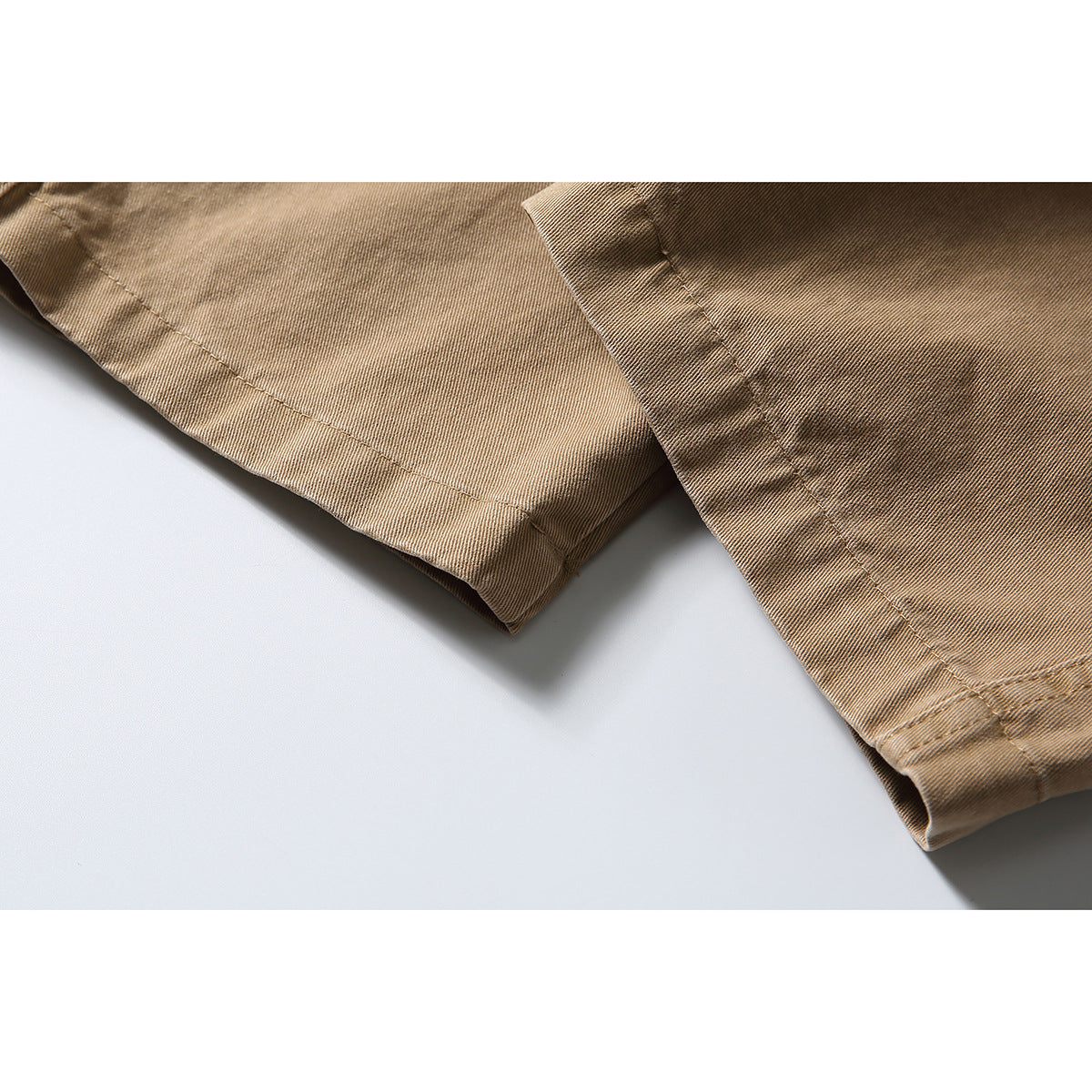 Close-up of the tan trousers' straight-leg hems and stitched seams.