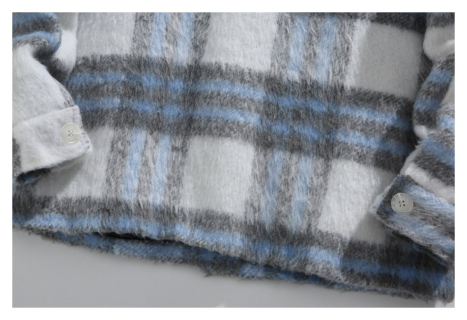 Close-up of the plaid garment's front and buttoned cuffs in fuzzy blue, gray, and white fabric.