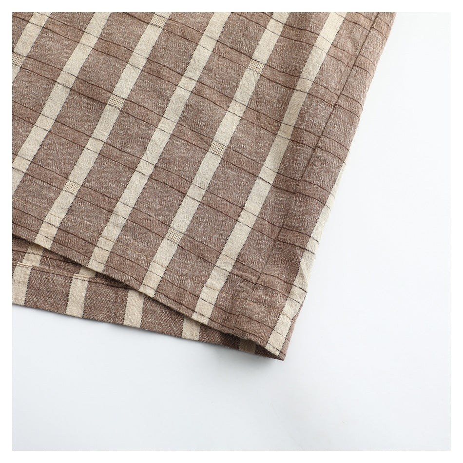 Close-up of a brown and cream plaid garment hem with visible stitching and folded edge.