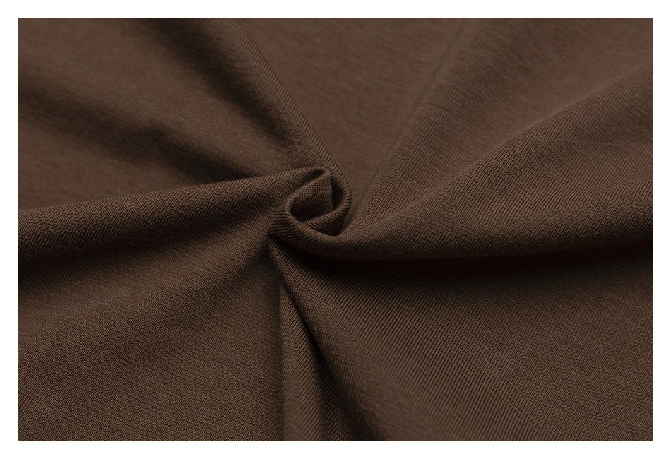 Close-up of brown fabric gathered into soft folds, showing its fine surface texture.