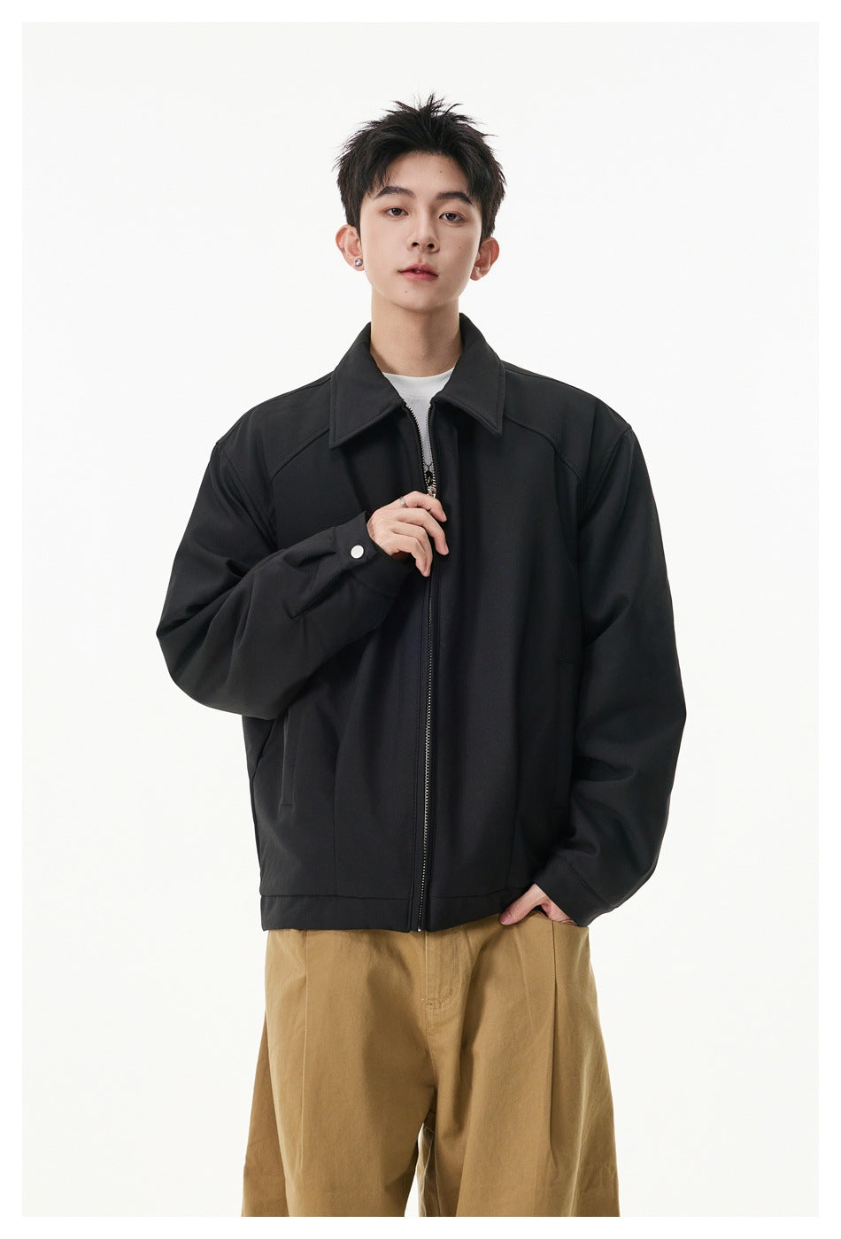 Model wearing a black zip-front jacket with a pointed collar, roomy sleeves and side pockets.