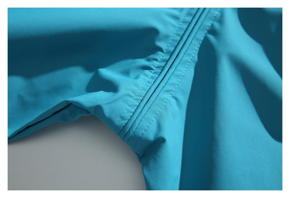 Close-up of a stitched seam on the turquoise jacket, with fabric panels visible.