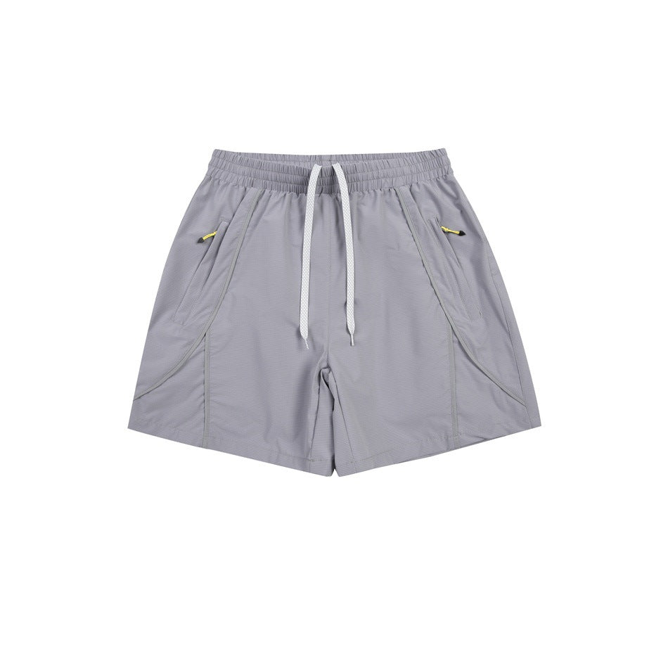 Gray athletic shorts flat lay with white drawstring, elastic waist and diagonal side pockets with yellow zip pulls