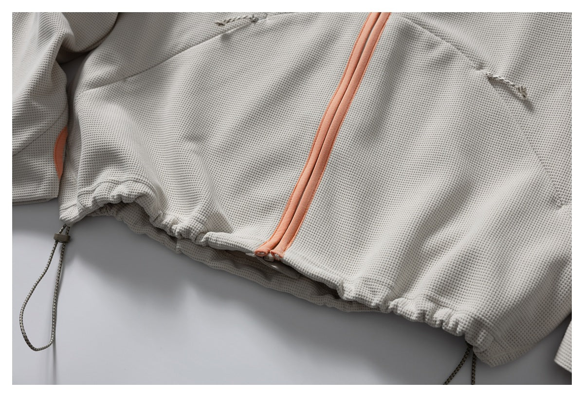Close-up of the jacket's peach-trimmed front zipper and gathered hem with adjustable drawcords.