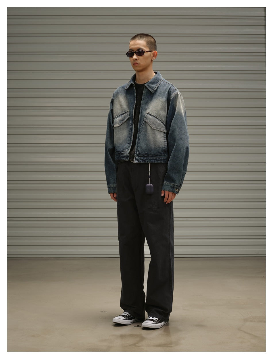 Full-length front view of a model wearing a faded blue denim jacket, black trousers, and sneakers.