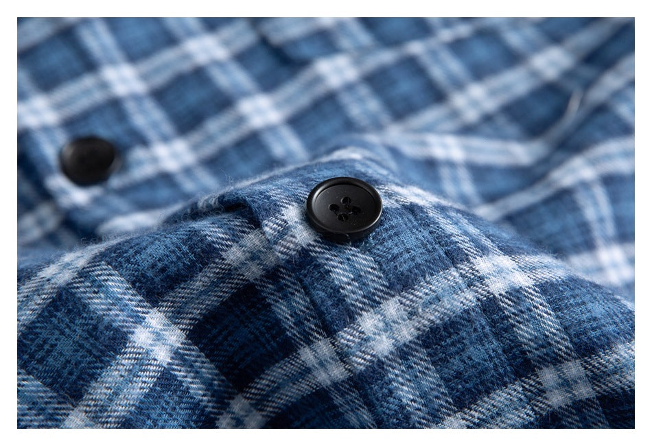 Macro view of blue-and-white plaid shirt fabric with a black four-hole button.