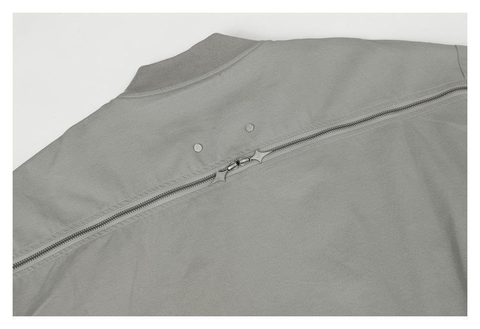 Close-up of the gray jacket's collar and back zipper with two small round fasteners.