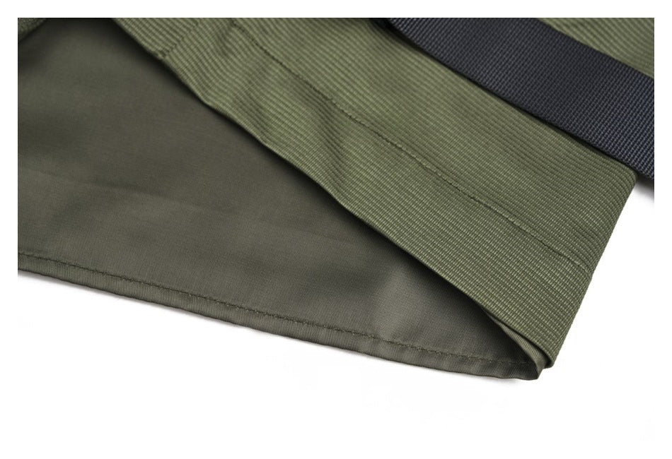 Close-up of an olive garment hem and wide ribbed band, with a dark contrasting fabric panel at the edge.