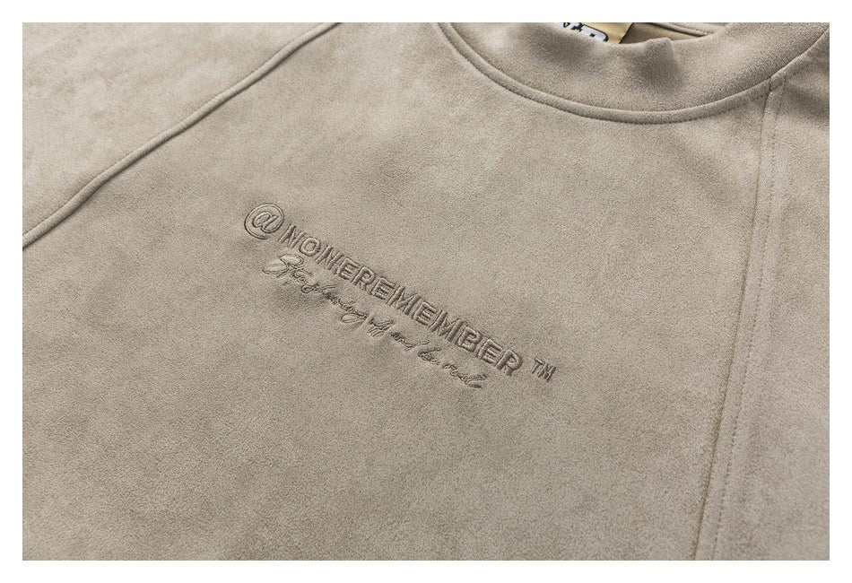 Close-up of embroidered lettering on the chest of a taupe crewneck sweatshirt.