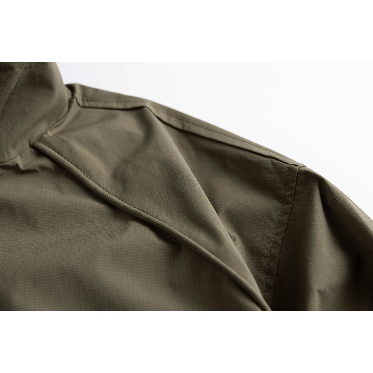 Close-up of an olive jacket's shoulder seam and sleeve construction.