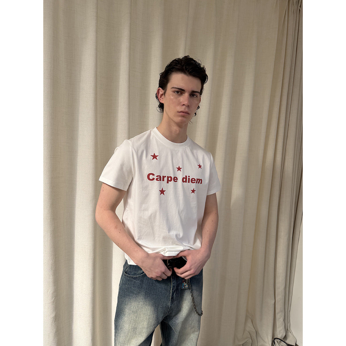 Closer view of a model wearing a white T-shirt printed with red Carpe diem lettering and stars.