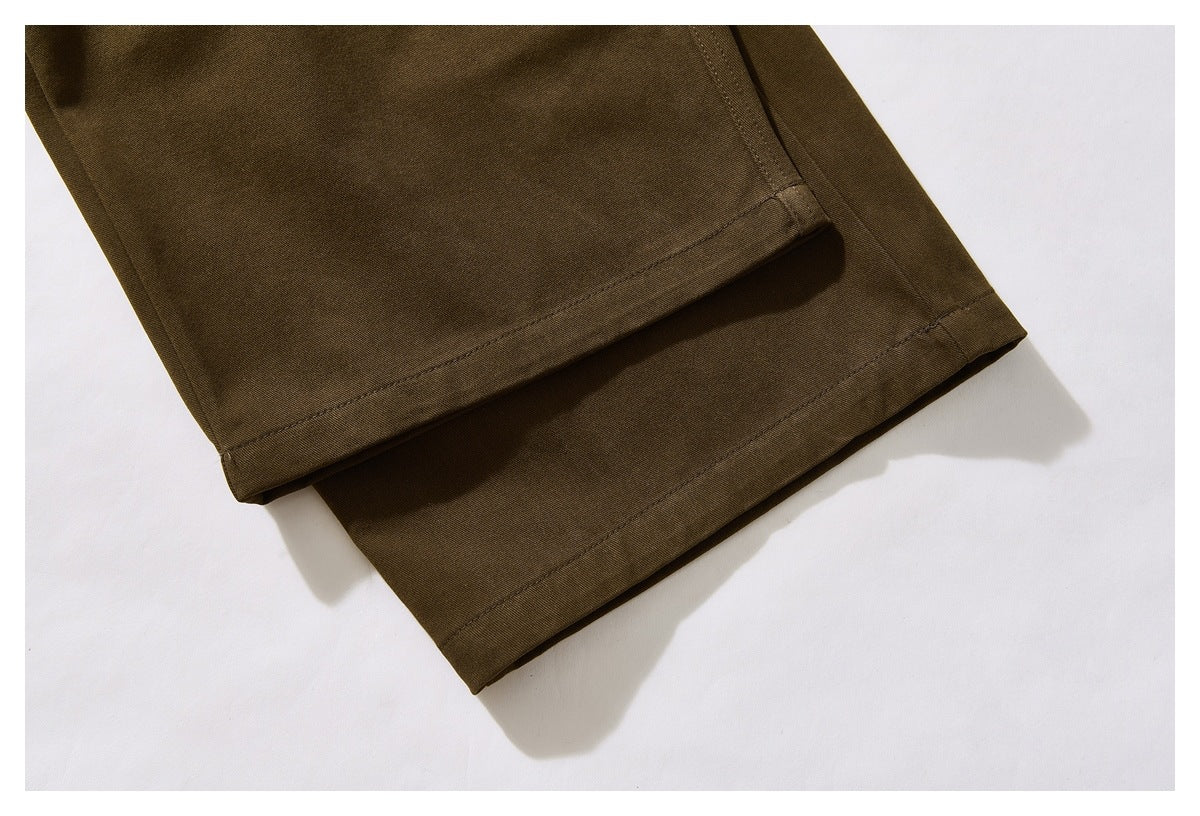 Close-up of the stitched hems of olive-brown trouser legs.