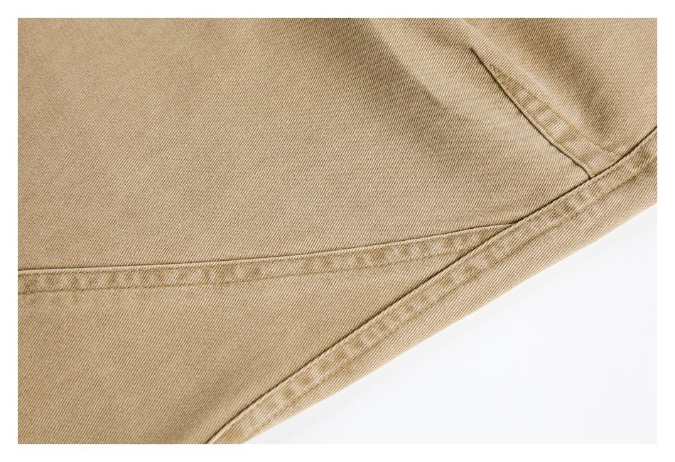 Close-up of tan pants fabric and curved double-stitched seams near a pocket.
