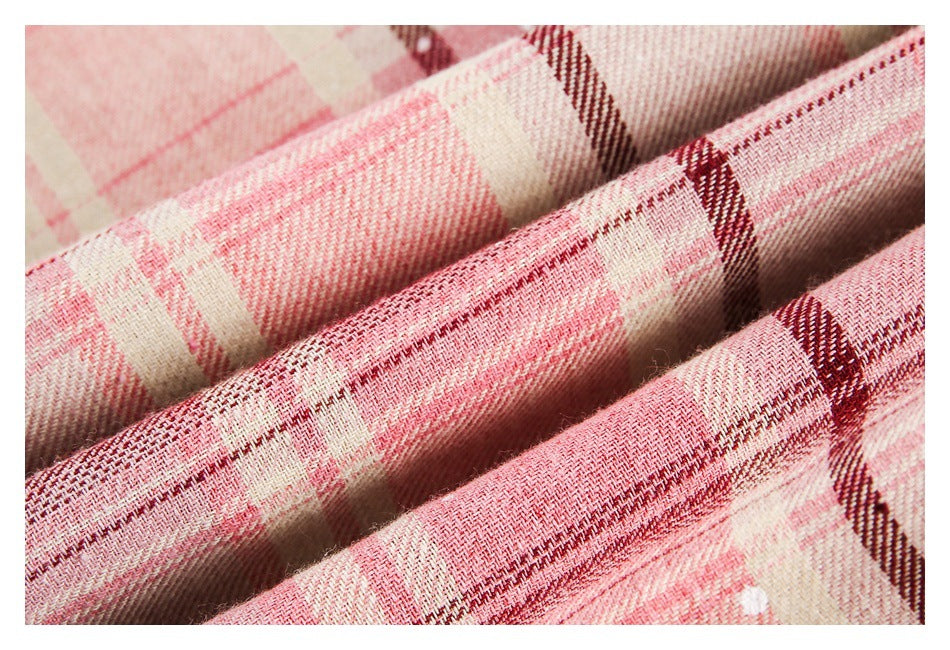 Close-up of pink and cream plaid fabric with burgundy stripes, draped in soft folds.