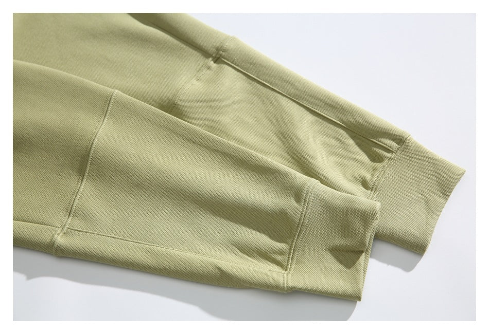Close-up of the muted olive hoodie’s sleeves and ribbed cuffs, laid flat on a light background.