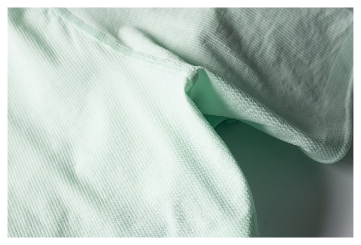 Close-up of mint green shorts showing the crotch seam and textured fabric.