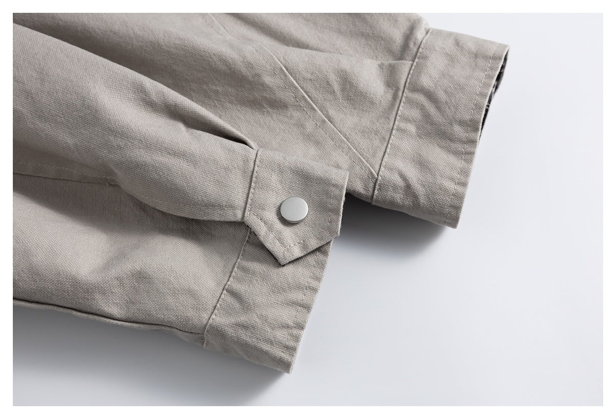 Close-up of a light gray jacket sleeve cuff with a snap-button tab and stitched seams.