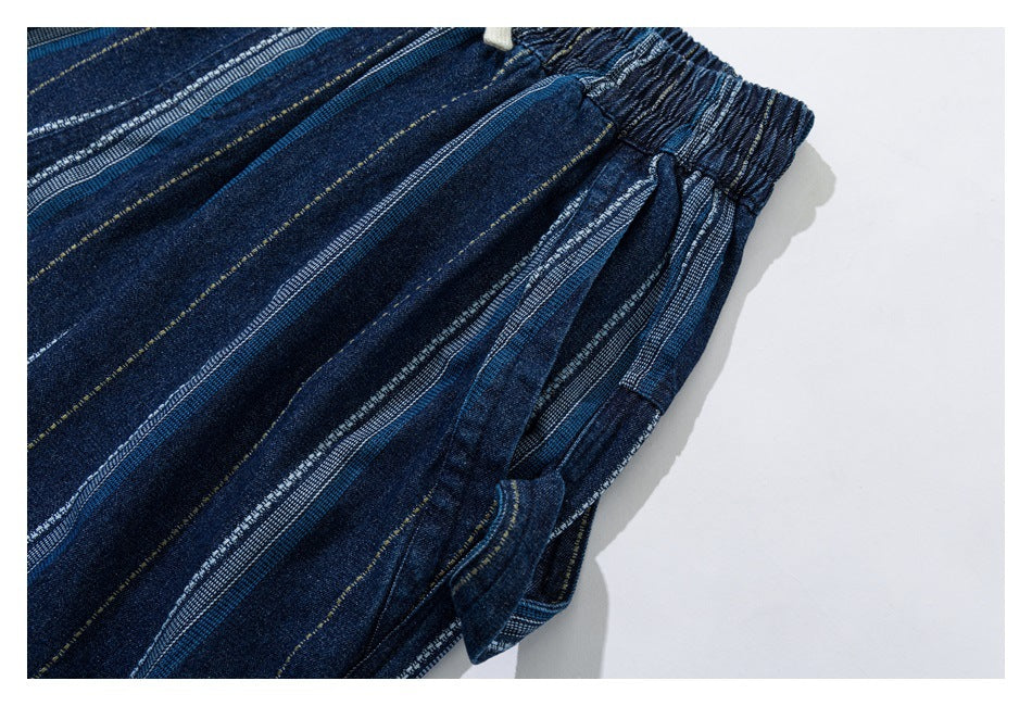 Close-up of a side pocket and gathered waist on dark blue striped trousers.