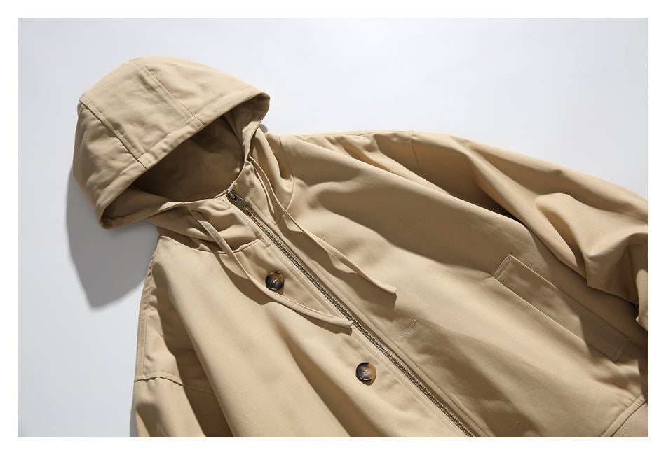 Angled front view of a tan hooded jacket with drawstrings, zipper, buttons, and a flap pocket.