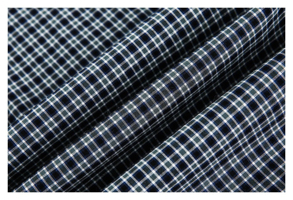 Close-up of dark navy and black fabric with a fine white grid check pattern, draped in folds.