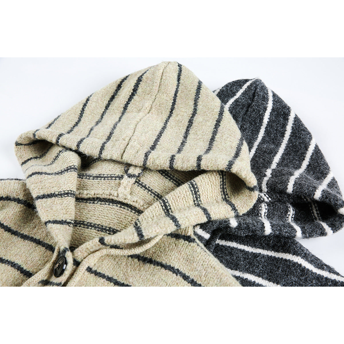 Close-up of two striped hooded cardigans, showing cream and charcoal knit texture, hood, drawstrings and button.