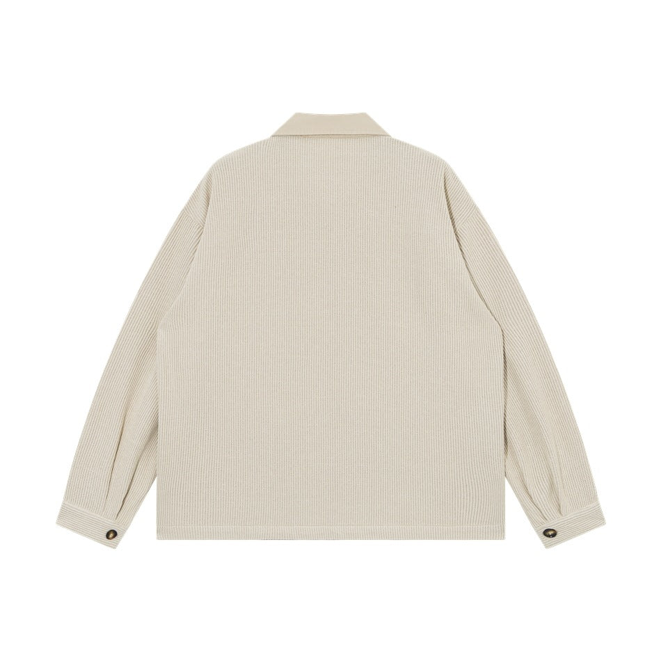 Back view of a cream collared jacket with long sleeves and buttoned cuffs.