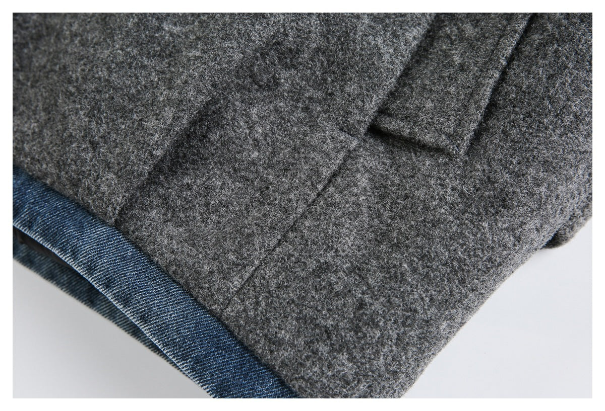 Close-up of the charcoal gray garment hem with blue denim-like edging and a small flap.