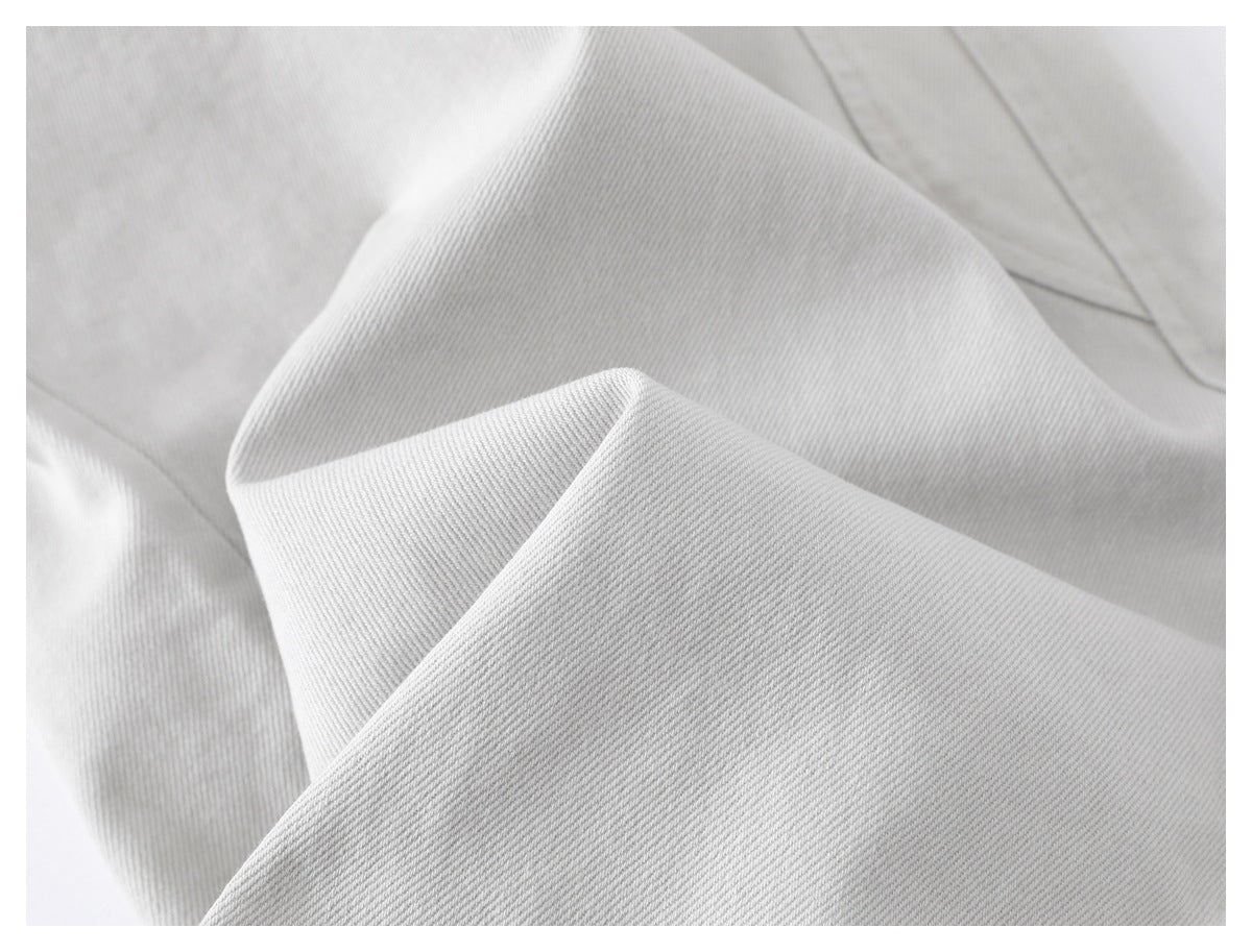 Close-up of light gray trouser fabric folded to show its diagonal weave and seams.