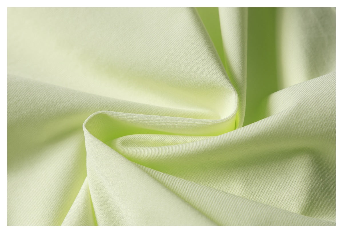 Close-up of pale lime fabric draped in folds, showing its fine surface texture.