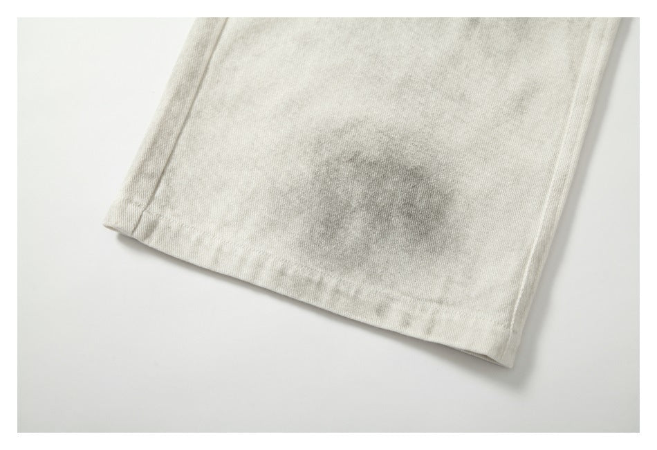 Close-up of the stitched hem on cream-gray mottled trouser fabric.