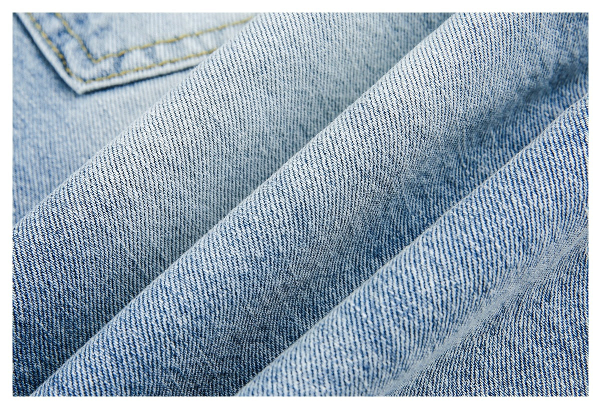 Close-up of folded light blue denim showing its diagonal weave and a stitched pocket edge.