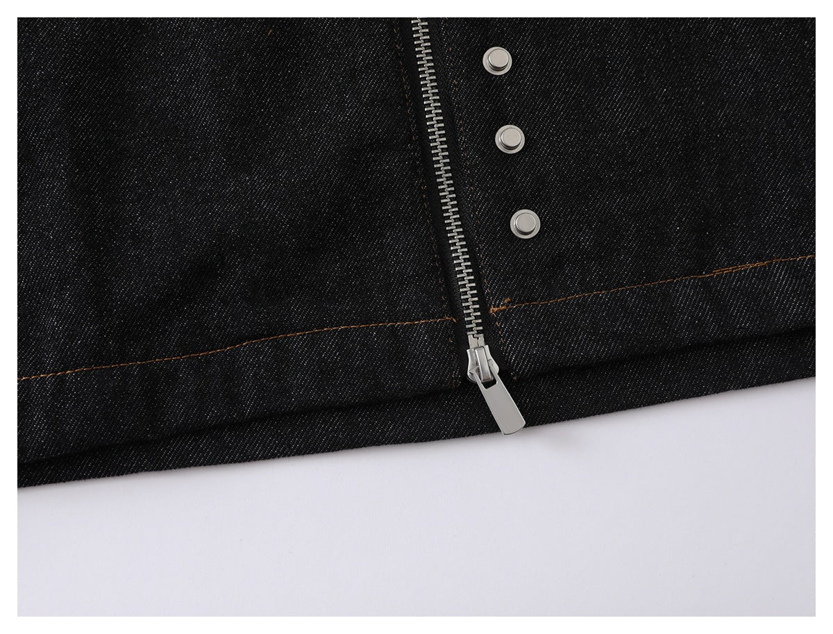Close-up of a silver zipper and three snaps on dark denim with orange stitching.