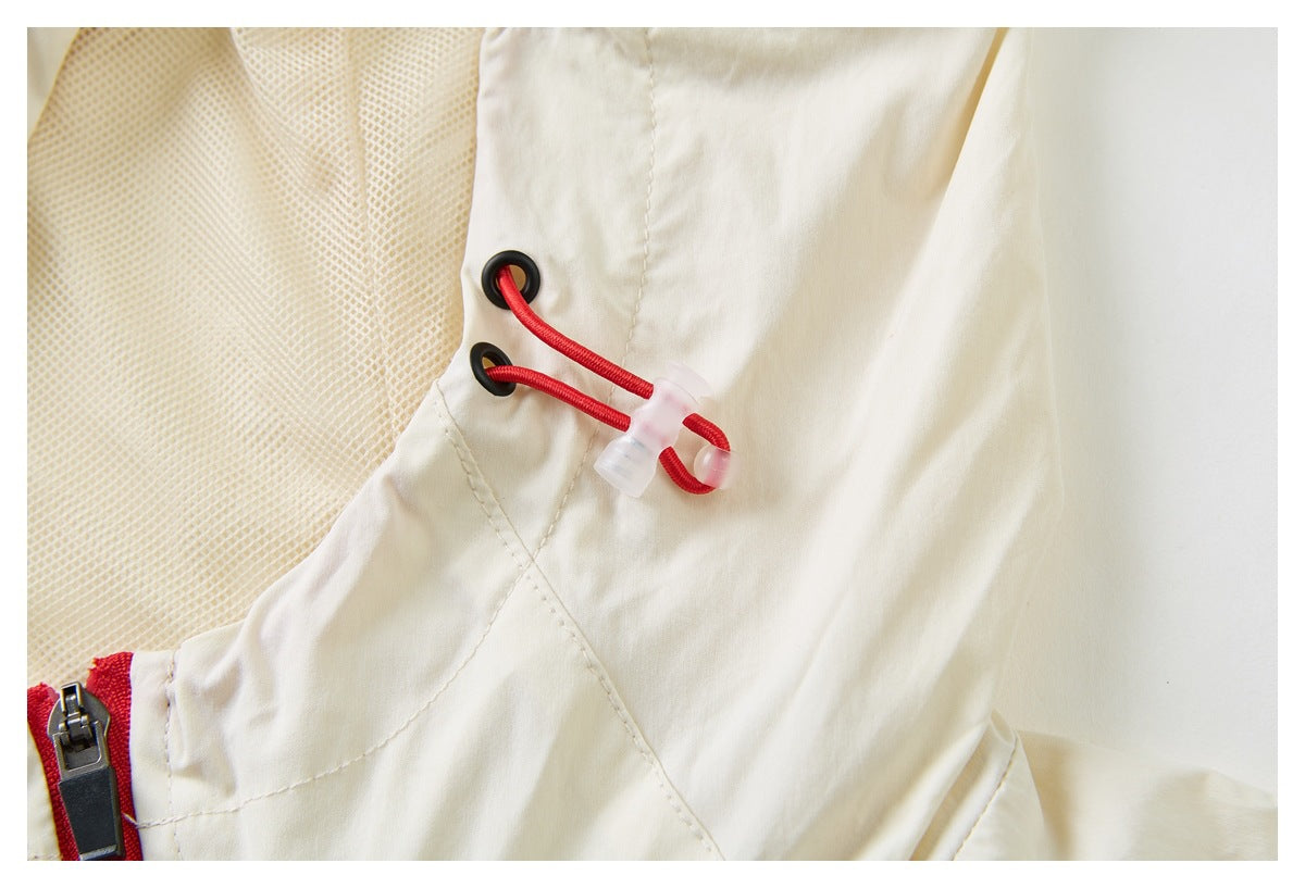 Close-up of a cream jacket hood with mesh lining, black eyelets, red drawcord and zipper edge.