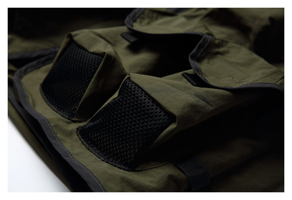 Close-up of two black mesh panels and flap pockets on an olive vest with dark trim.