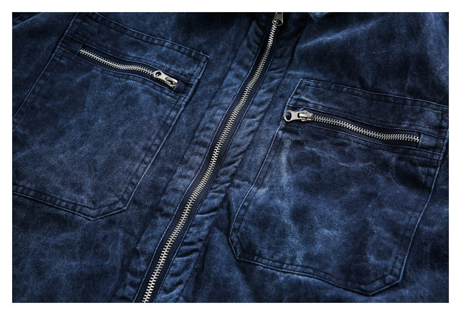 Close-up of a dark blue washed jacket front with a central zipper and two zippered chest pockets.
