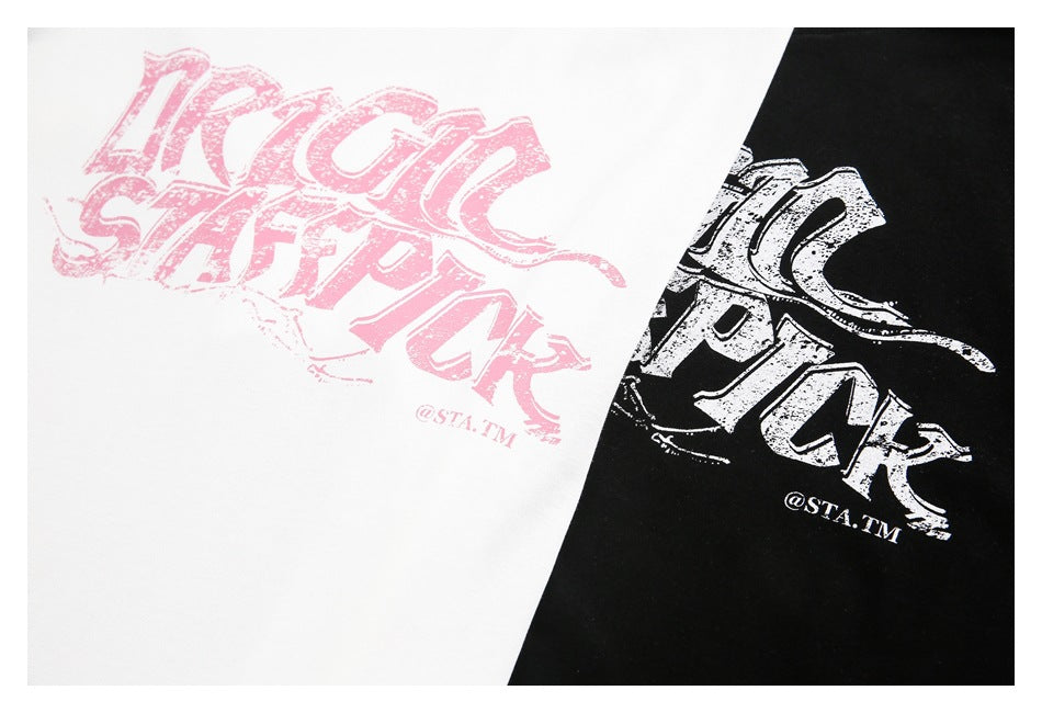 Close-up of white and black T-shirts with distressed pink and white graphic prints.