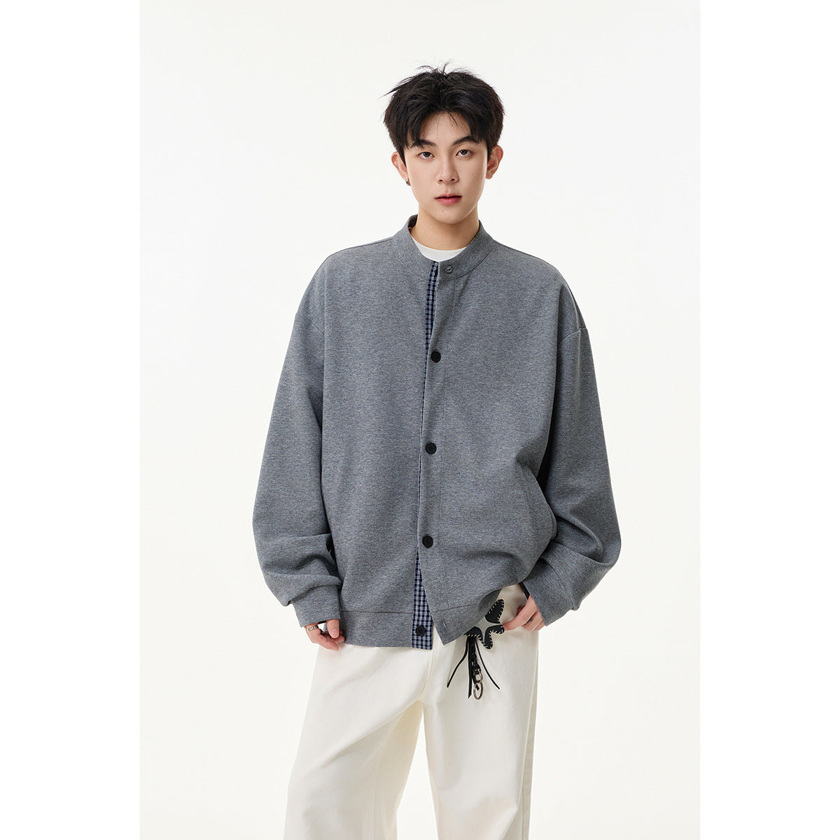 Model wearing an oversized gray button-front jacket with a stand collar and narrow plaid inset.