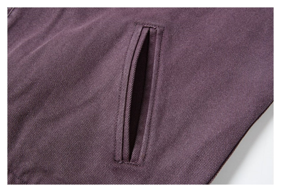 Close-up of a vertical welt pocket on plum-colored textured jacket fabric.