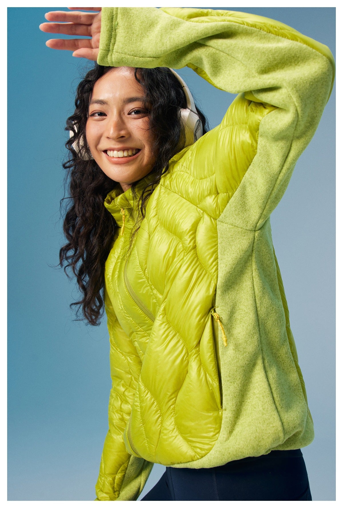 Close-up of a smiling woman in a lime quilted jacket with pale green sleeves and thumbholes.