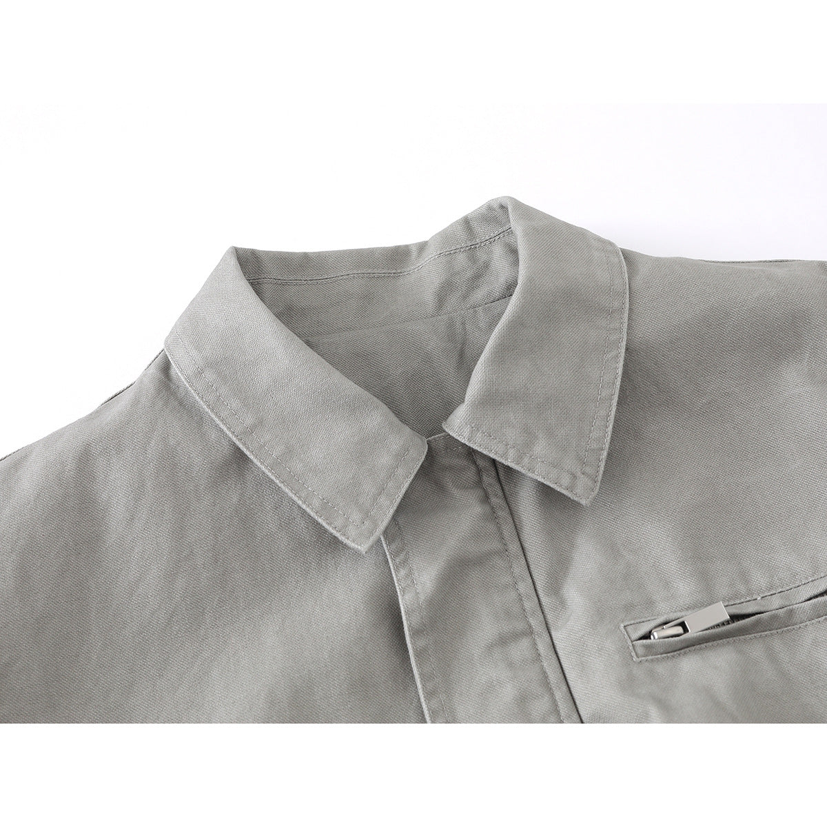 Close-up of a light gray jacket's pointed collar, front placket, and narrow chest pocket.