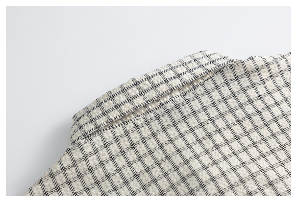Close-up of cream fabric with a black windowpane plaid pattern.