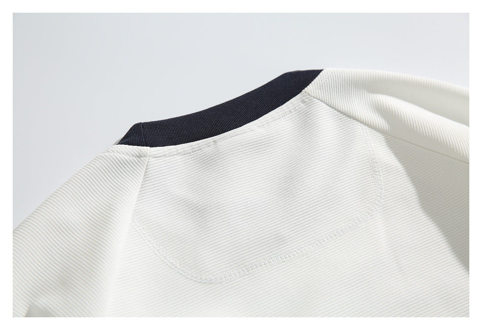 Close-up of a white garment's dark navy ribbed neckline and curved stitched seam.