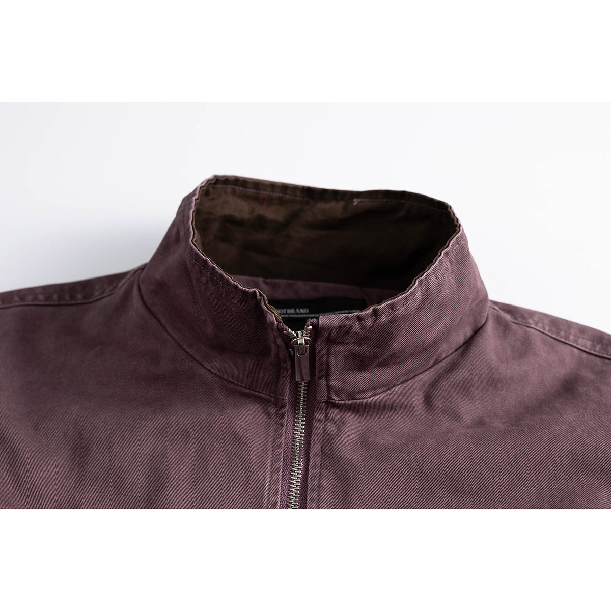 Close-up of a plum jacket's stand collar and centered metal front zipper.