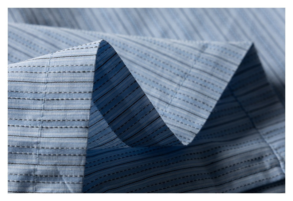 Close-up of folded, pointed collar-like edges on light blue striped fabric.