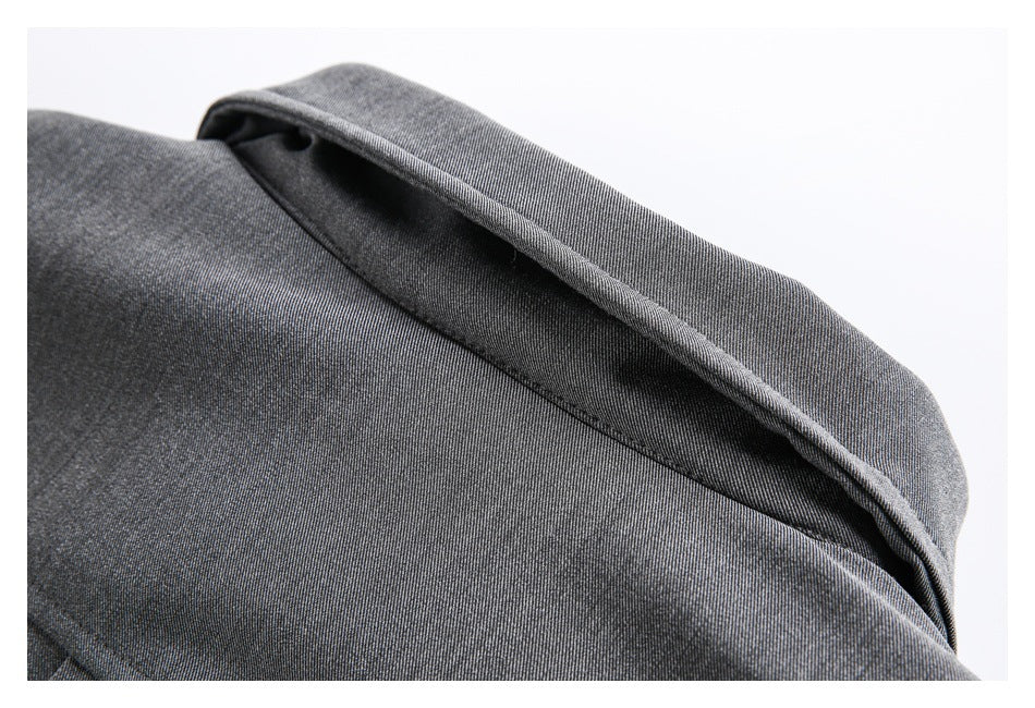 Close-up of charcoal gray garment fabric folded over an edge, showing the dark inner side and stitching.