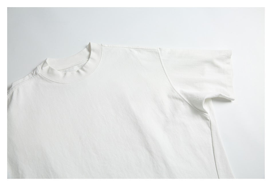 Close-up of the white T-shirt's high crew neckline, shoulder seam, and short sleeve.