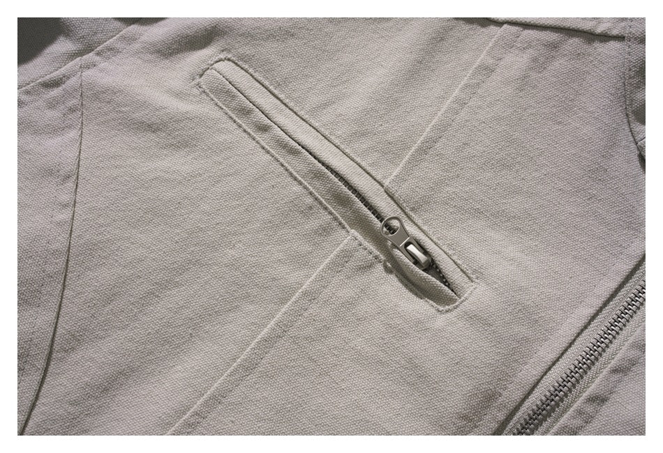 Close-up of a diagonal zip pocket on the light gray jacket.