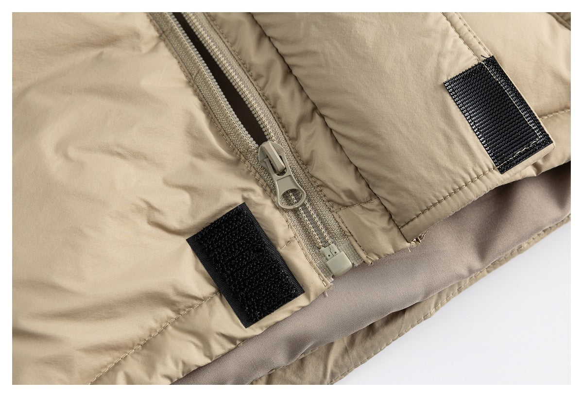 Close-up of a beige padded jacket's front zipper and black hook-and-loop fastening tabs.