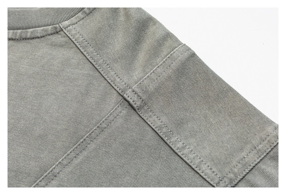 Close-up of the gray shirt’s shoulder and sleeve seams with visible stitching and a ribbed collar edge.
